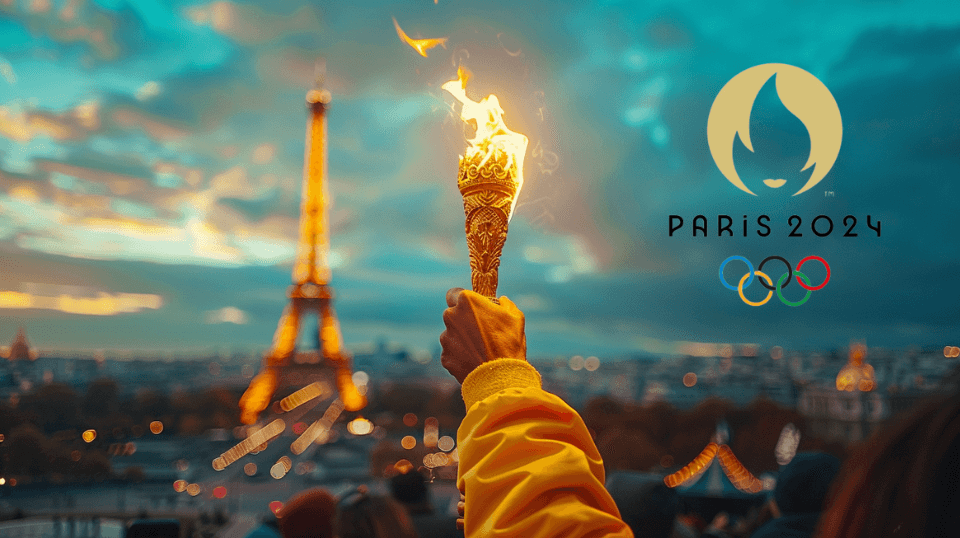 A male hand holding the Olympic flame with the Eiffel Tower in the background